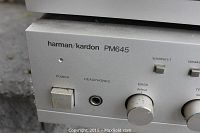 Close-up front left portion of Harman Kardon PM 645 amplifier showing power switch, headphone jack, and bass control knob.