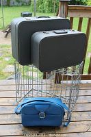 Pair of vintage hard shell suitcases stacked on a metal rack with the blue leather travel tote bag placed in front on the floor, showing size and condition.