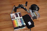 Digital leg exerciser with assorted fitness tapes, CDs, and GPX BC111 CD boom box on hardwood floor
