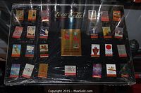 Full view of the Coca Cola Olympic pin set mounted on black board in original box with plastic wrap