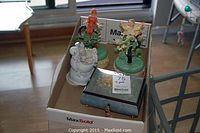Four items in a cardboard box including two Enesco fairy musical figurines, a bunny wedding musical figurine, and a musical jewelry box
