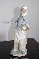 Angle showing woman facing front with arm extended, basket in hand, and dog beside her.