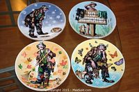 Four collector plates on table depicting four seasons with Emmett Kelly Jr. clown and dog character