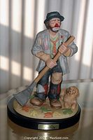 Front view of the Autumn figurine showing the clown figure holding a rake with a small dog at its side, standing on a leaf-decorated base with a nameplate.