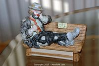 Front view of Emmett Kelly Jr. figurine sitting on a wooden bench with 'Wet Paint' sign.