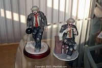 Photo showing both Emmett Kelly Jr. clown figurines, one standing with bowling ball, the other seated tying shoe.
