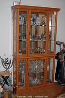 Full view of the oak china cabinet showing upper and lower glass doors and interior items for scale.