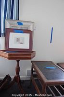 View of the two wooden end tables and a stack of framed prints resting on the octagonal table.