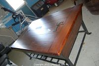 Full view of rustic wooden coffee table showing closed hinged top with barn door-style iron hinges and iron legs.