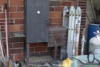 Full front view of black steel vertical offset smoker with firebox and wheels