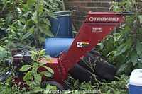 Full view of red Troy-Bilt chipper surrounded by foliage
