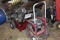 Two gas powered pressure washers side by side, the Husky (front) and Generac (back), both equipped with wands and hoses, showing used condition.
