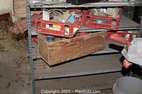 Rusty metal cart with shelves holding red plastic crates and a wooden box, showing assorted small parts and tools inside crates.