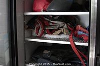 Photo of horse care items stored on shelves inside a metal cabinet including blankets, leads, wraps, and other horse accessories.