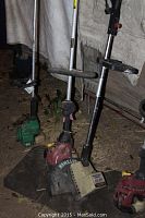 Four gas-powered weed wackers standing upright showing various brands and parts including Craftsman, Homelite, Featherlite