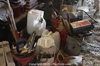 Overview of lot includes plastic gas cans, tool bags, and assorted containers with tools and hardware in a barn environment.