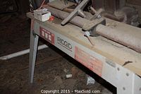 Close-up of the lathe bed and brand sticker reading "Rigid Wood Lathe" in a dusty condition.