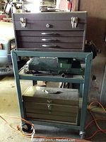 Green rolling cart with three toolboxes on shelves