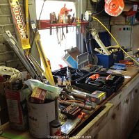 Workbench surface loaded with assorted tools, hardware containers, and tool cases