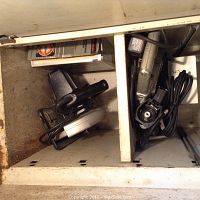 Photo shows two shelves in a metal cabinet with a Craftsman circular saw, Rotozip tool, and cords.