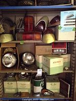 Multiple shelves showing round sealed beam headlights in boxes, chrome fog lights, assorted tail light and turn signal lenses