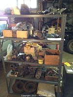 Five-tier metal shelving unit filled with assorted auto parts, boxes and loose components