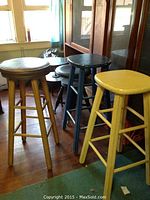 Five wooden stools grouped together, showing variety of colors and seat types.