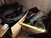 Two open boxes containing assorted hoses, wiring harness, shift lever parts and headlight assemblies