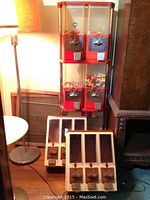 Four-unit red gumball machine with colorful gumballs on top and two beige vending machines below