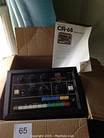 Roland CompuRhythm CR-68 in open box with owner’s manual propped behind