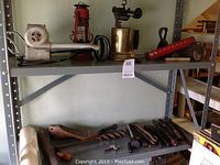 Shelf with various vintage tools and equipment including blow torch, lantern, ice tongs, and hand tools.