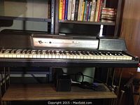 Full front view of Wurlitzer electronic piano on trestle legs, keyboard and control panel visible