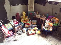 Wide view of various vintage plush toys including Big Bird, Donald Duck, clowns, bears, and a small table with toys.