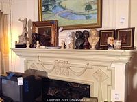 Photo of mantel showing four framed copper busts, various smaller busts and decorative plates