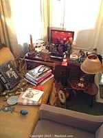 Wide view of room corner showing music themed items on tables and sofa including lamp, phone, bottles, candy dishes and books.