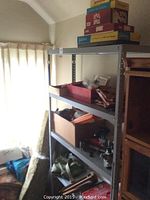 Wide view of metal shelving with multiple board games stacked on top and boxes on shelves below.