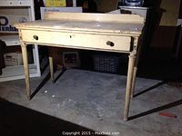 Front view of the vintage wooden table showing the drawer and beaded legs.