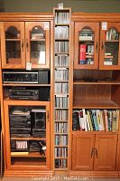 Full view of tall wooden CD cabinet with glass doors and interior shelves, holding CDs and books.