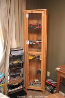Full view of the tall pine curio cabinet with glass door displaying various model cars inside.