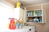 Laundry detergent and cleaner bottles on top of washing machine and inside wall cabinet