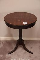 Full view of round wooden Duncan Phyffe style side table with single pedestal and three legs.