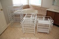 Overall view of three white wire basket shelving units in a bathroom