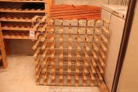 Two wooden wine racks shown: a large grid-style rack and smaller fold-up rack placed on top.