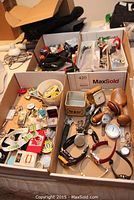 Overview of three boxes containing mixed lot items including watches, clocks, tie clips, lighter, keychains and pins