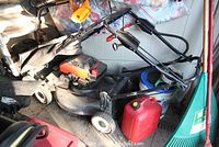 Full side view of the red lawn mower showing handle, wheels, and engine area