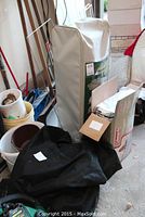 Green Coleman air mattress in carrying case standing upright with other camping supplies around