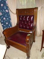 Front-right view showing carved oak arms, tufted leather back