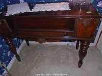 Front view of desk with turned legs, carved details, and two doilies on top