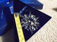 Close-up showing Swarovski 2002 crystal snowflake ornament inside blue velvet-lined box with measuring tape indicating size approximately 7 cm.