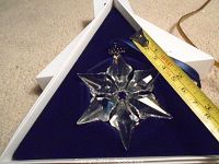 Clear Swarovski crystal snowflake ornament inside original white box lined with navy blue velvet, measuring approximately 3 inches wide.
